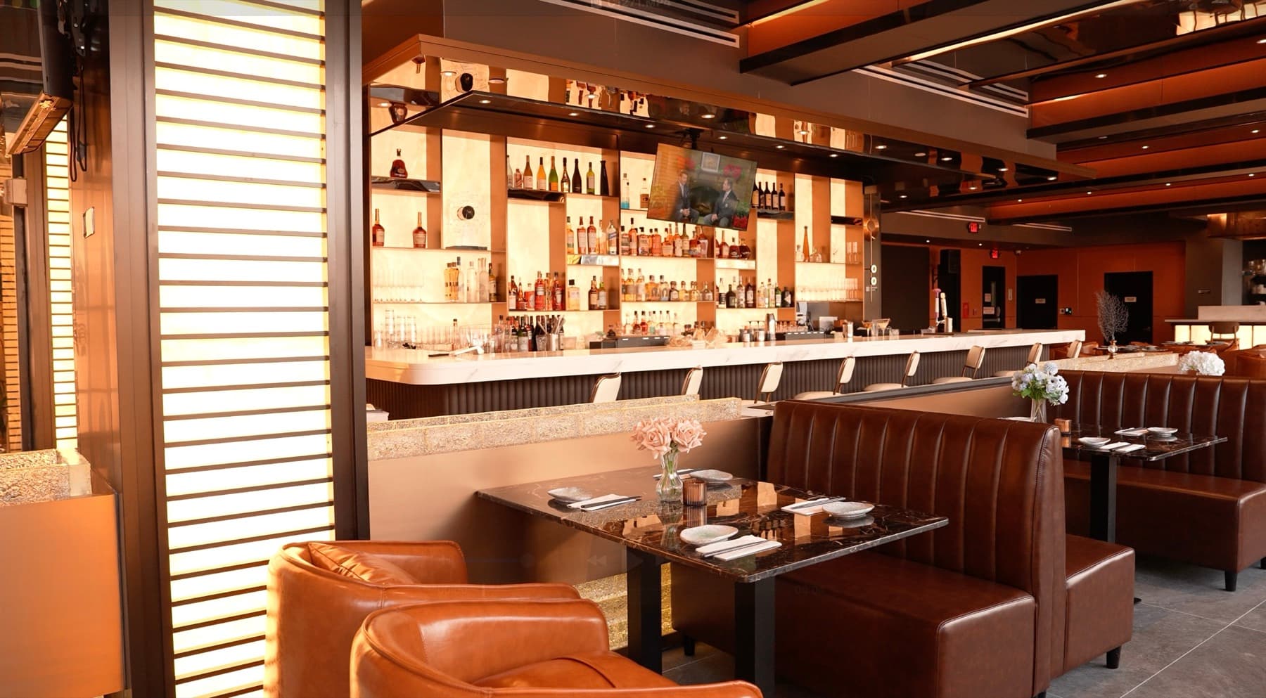 Cocktail bar with amber backlit liquor wall